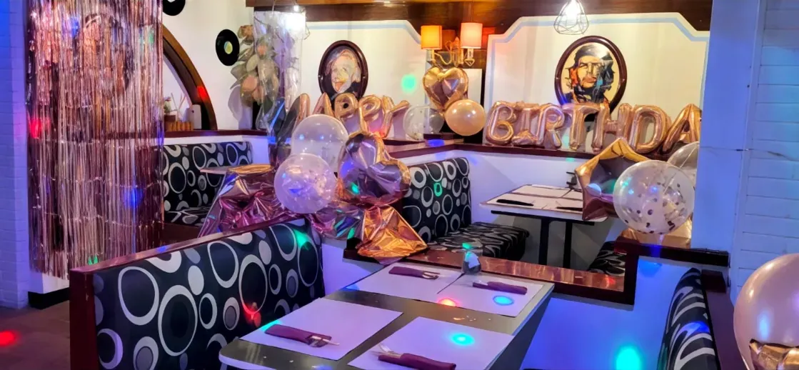 Una persona con una diadema sonríe sentada en una mesa de una cafetería al aire libre con un vaso de sangría