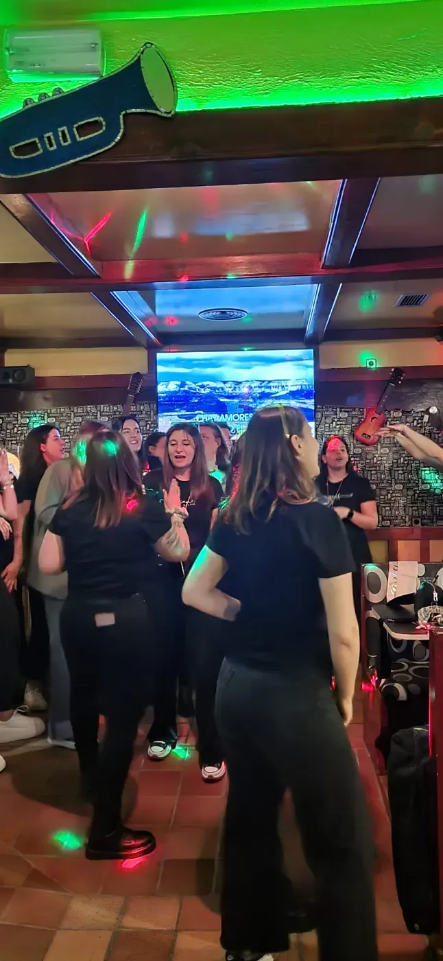 Una mujer pelirroja está sentada en la barra de un bar mientras un hombre, al fondo