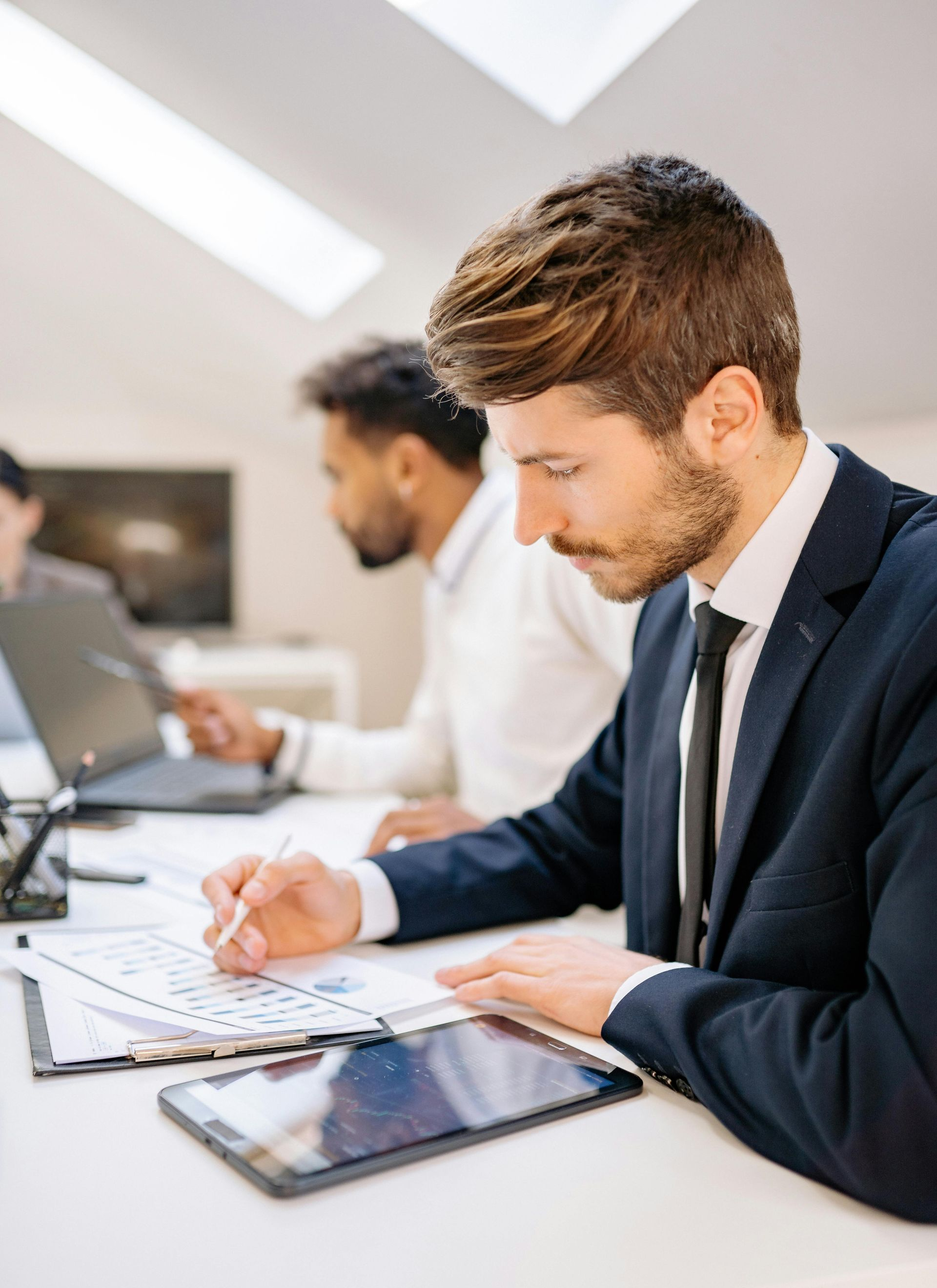 Un profesional vestido de traje revisa documentos en un escritorio en una oficina luminosa