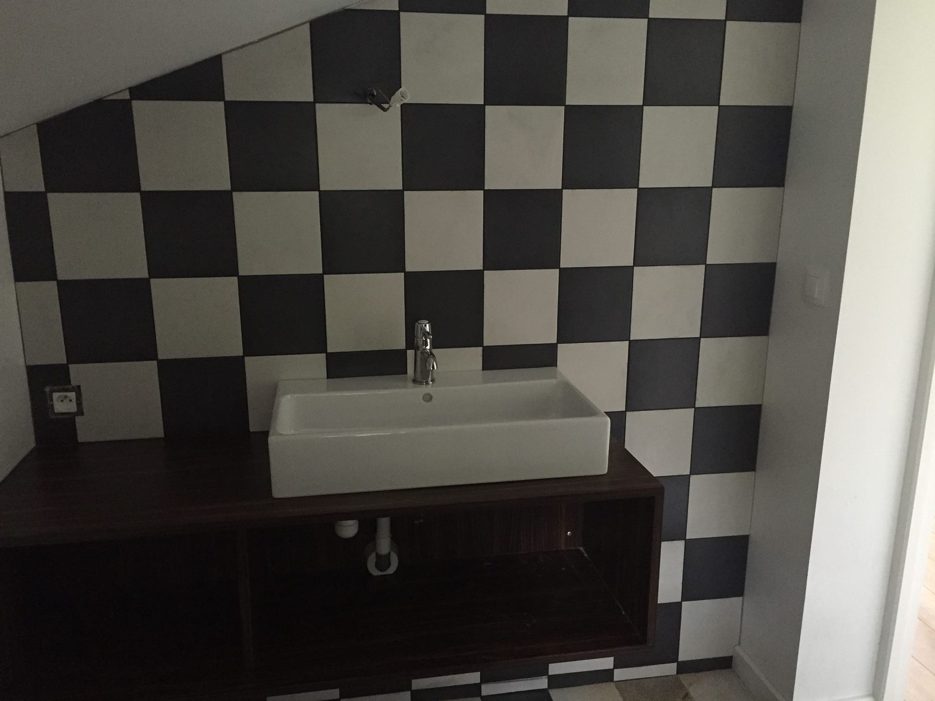 Damier noir et blanc dans une salle de bains, focus sur vasque
