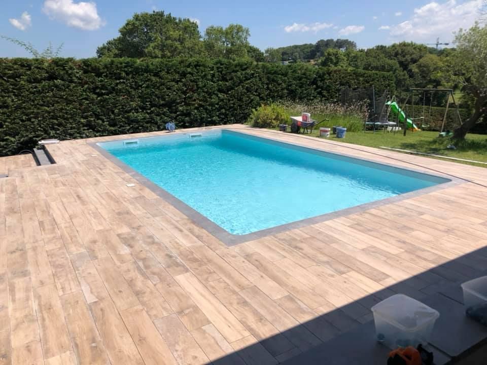 Piscine creusée et grande terrasse de piscine en carrelage aspect bois