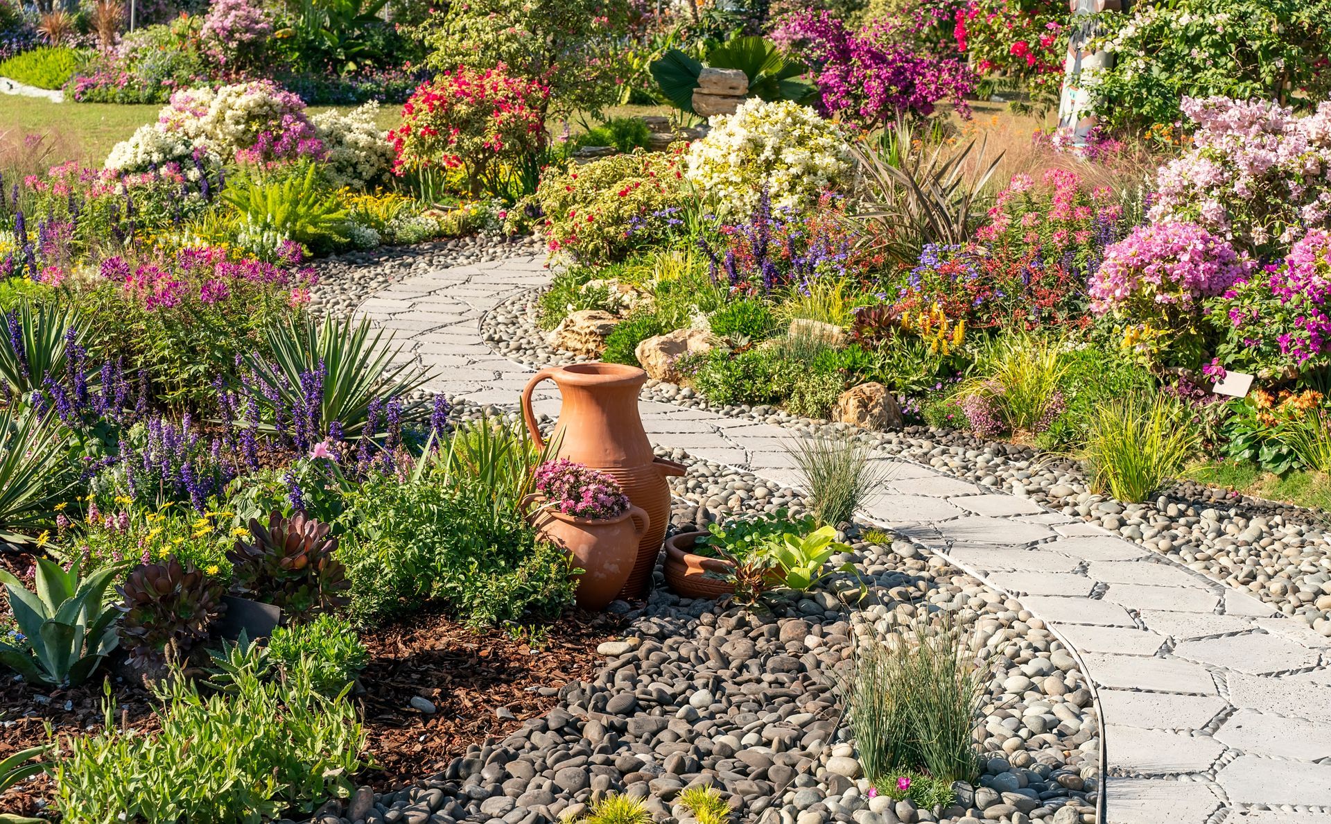 Allée de jardin passant entre plusieurs bosquets fleuris