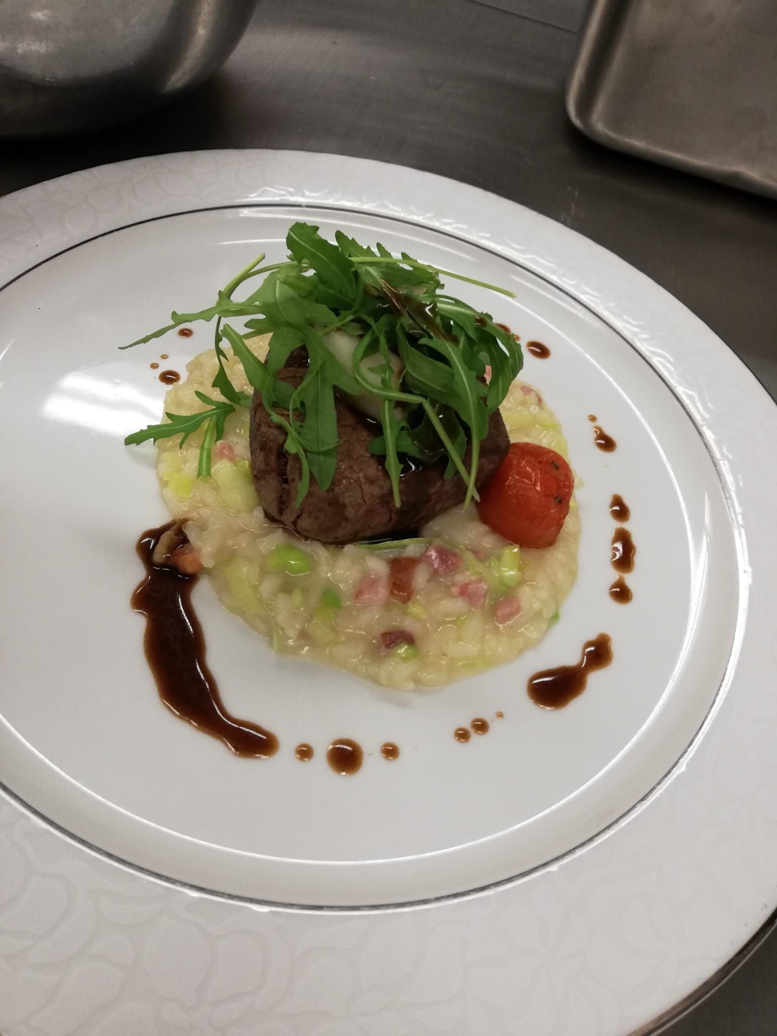 Gourmet-Gericht mit Gemüse, Sauce und roter Garnitur auf einem weissen Teller