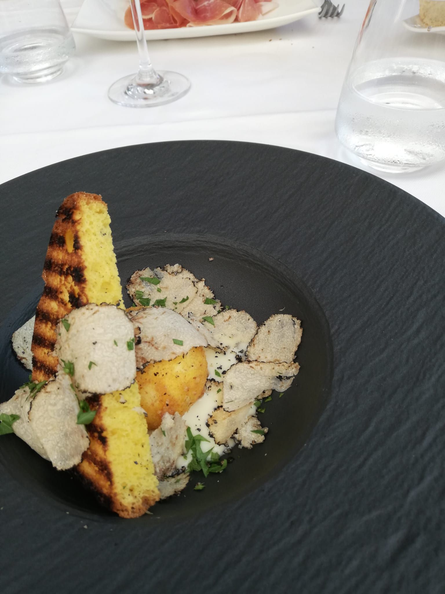 Schwarzer Teller mit gegrilltem Fisch, Jakobsmuscheln und Gemüse in einem gehobenen Restaurant