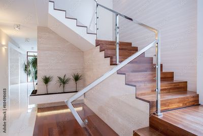 Escalier intérieur moderne avec marches en bois, rampe en verre et murs blancs dans un intérieur lumineux