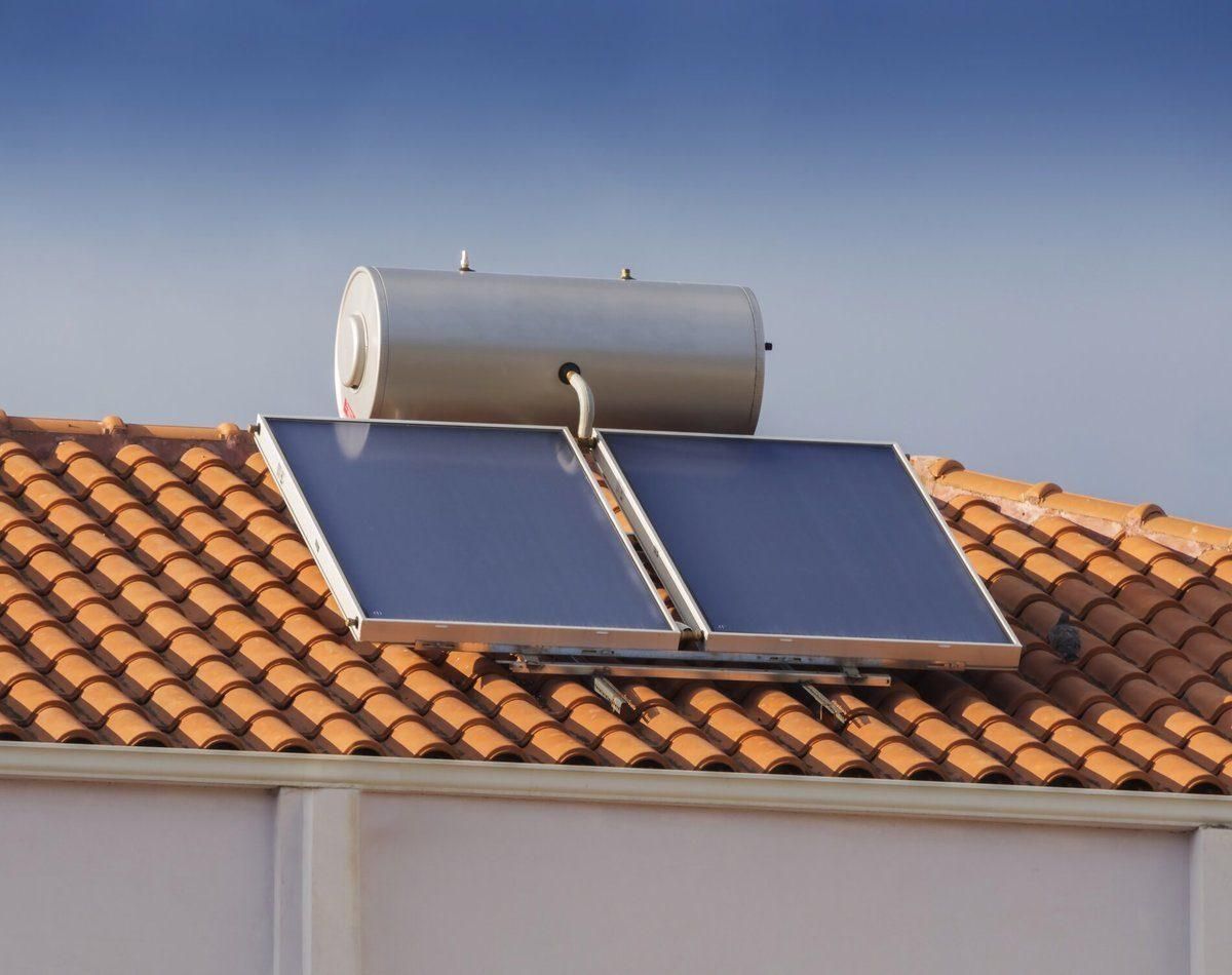 Dos paneles solares instalados en un tejado de tejas, bajo un cielo despejado