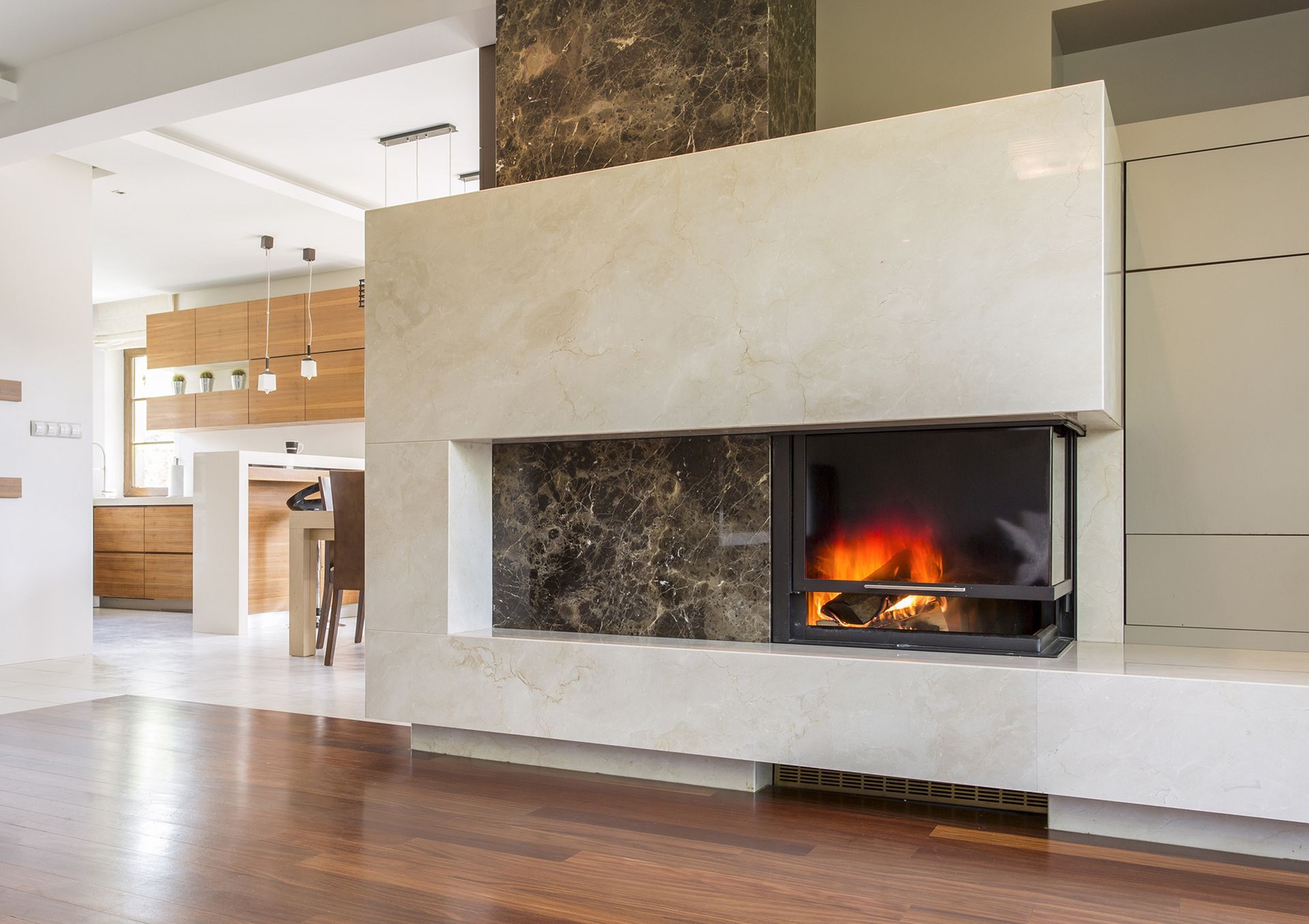Uma cozinha com bancadas de granito, armários brancos, pisos de madeira e bancos.