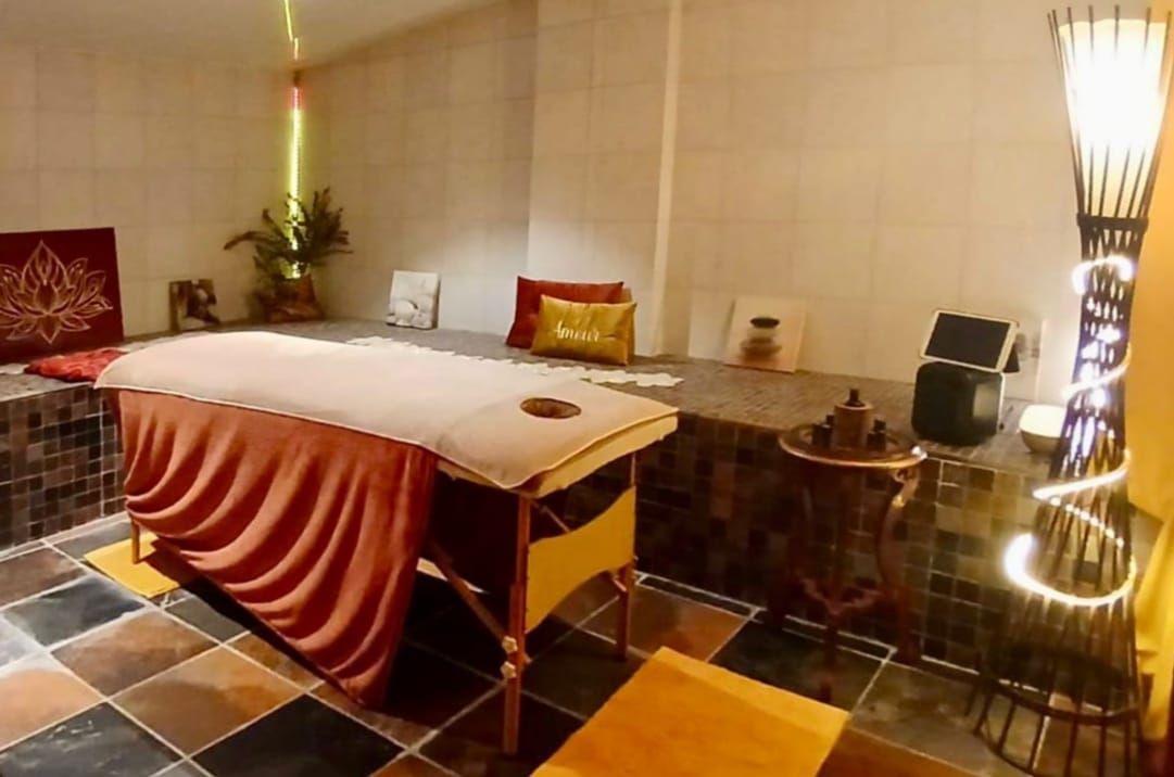 Table de massage dans une salle de spa tamisée, à l'éclairage chaleureux et au sol carrelé