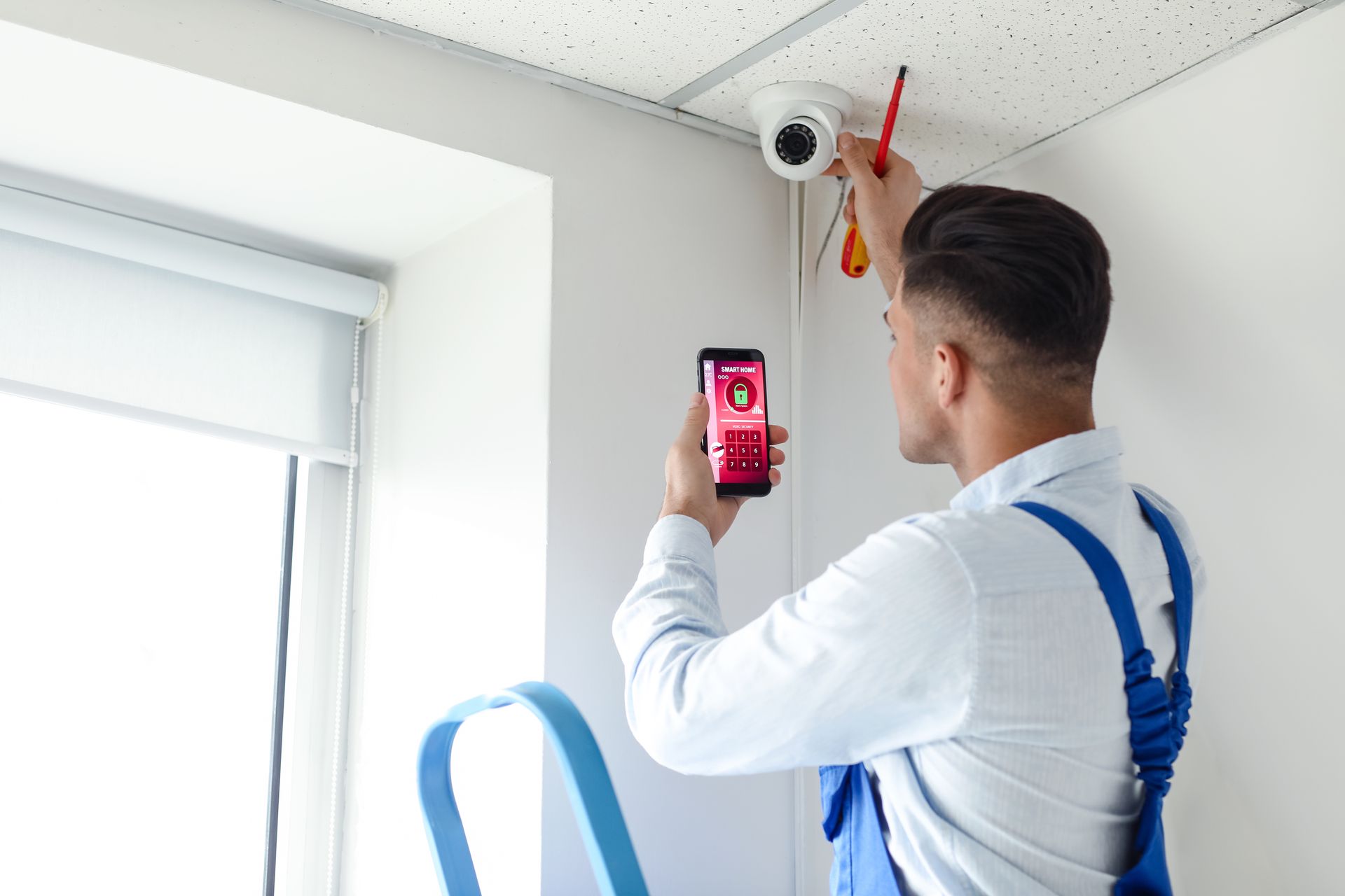 Un technicien installe un détecteur de présence.