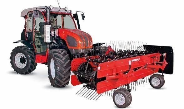 Roter Traktor mit Heurechenaufsatz, für landwirtschaftliche Zwecke.