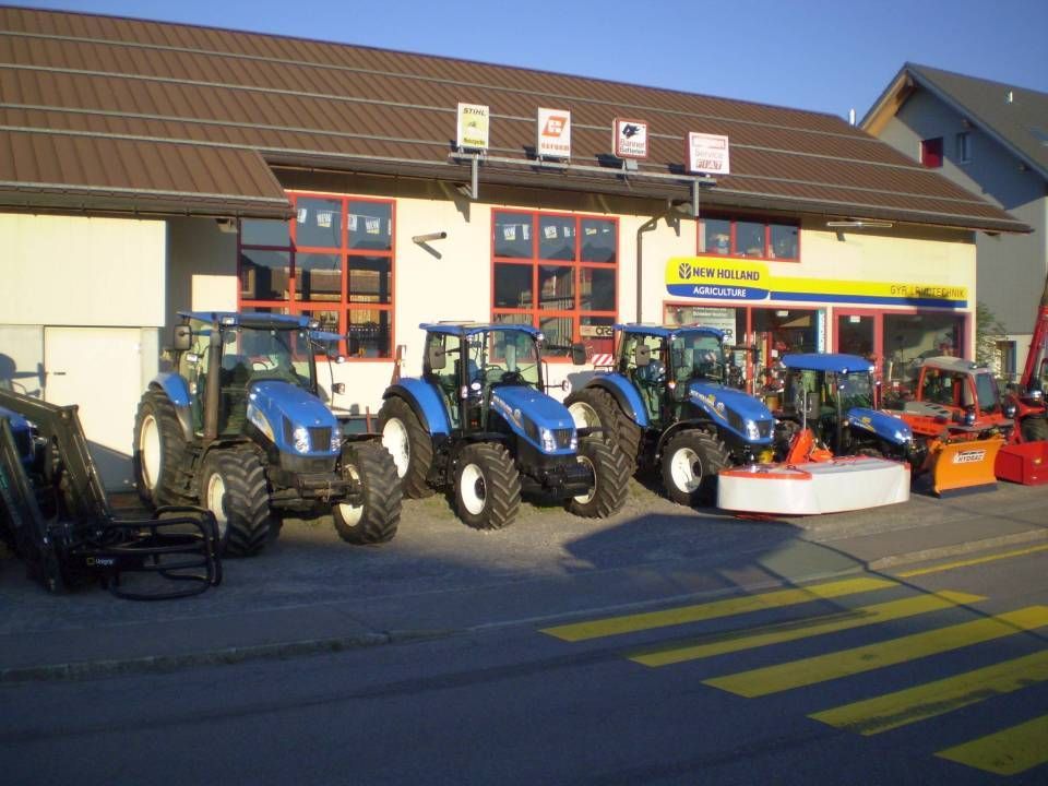 Blaue Traktoren standen vor einem Gebäude, auf dem der Firmenname „SCHWENK AG“ deutlich zu sehen war.