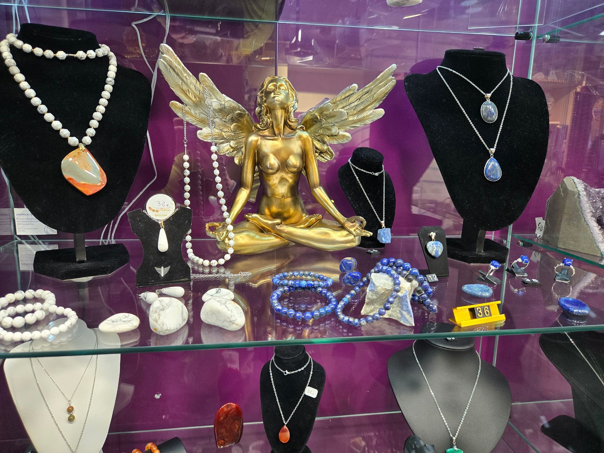 Présentoir à bijoux avec colliers, bagues et bracelets sur des supports autour d'une figurine ailée dorée