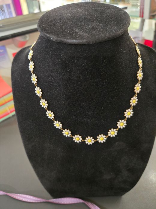 Collier marguerite orné de breloques en forme de fleurs, présentées sur un buste en velours.