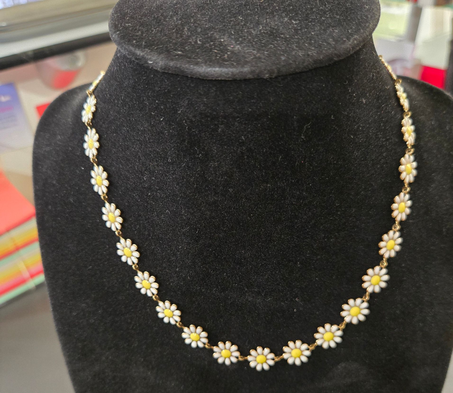 Un collier de marguerites aux fleurs présenté sur un buste en velours.