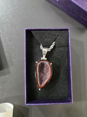 Pendentif en forme de larme sur une chaîne en argent dans un écrin à bijoux.