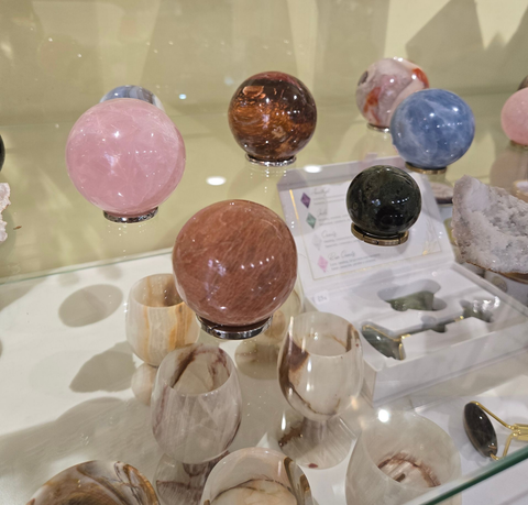 Sphères décoratives en cristal sur des supports transparents dans une vitrine à éclairage tamisé.