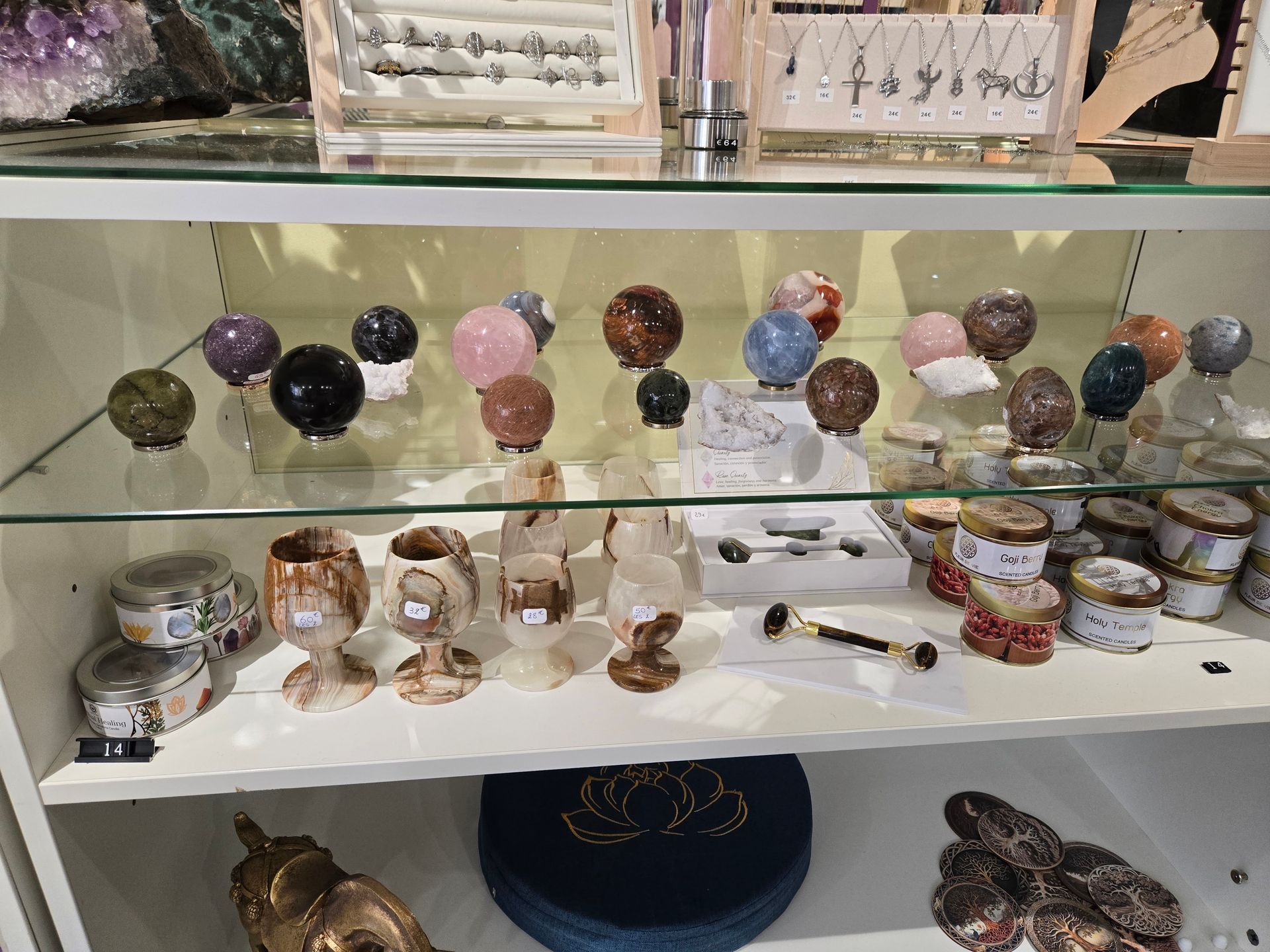 Des étagères en verre présentent un assortiment de sphères en cristal, de figurines et de petits pots décoratifs.