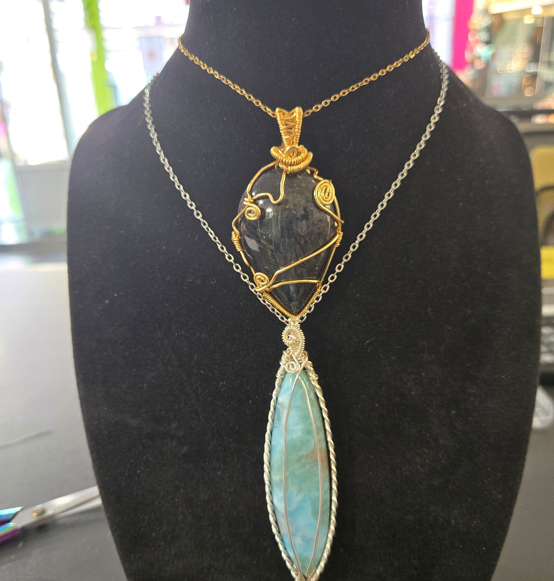 Collier en or avec pendentifs en pierres précieuses sur un buste d'exposition en velours.