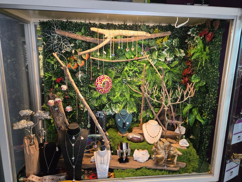 Aménagement de plantes d'intérieur avec une végétation luxuriante, des guirlandes lumineuses et des vases décoratifs dans un coin lumineux près de la fenêtre.