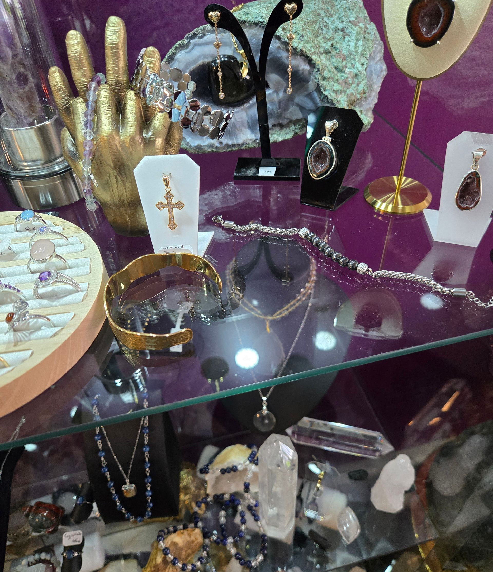 Présentoir en verre de bijoux en or et en argent (bracelets, colliers et bagues) sur support en tissu.