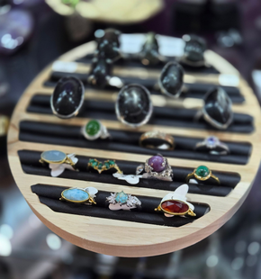 Bagues ornées de pierres précieuses assorties, présentées sur des supports dans une vitrine de bijouterie.