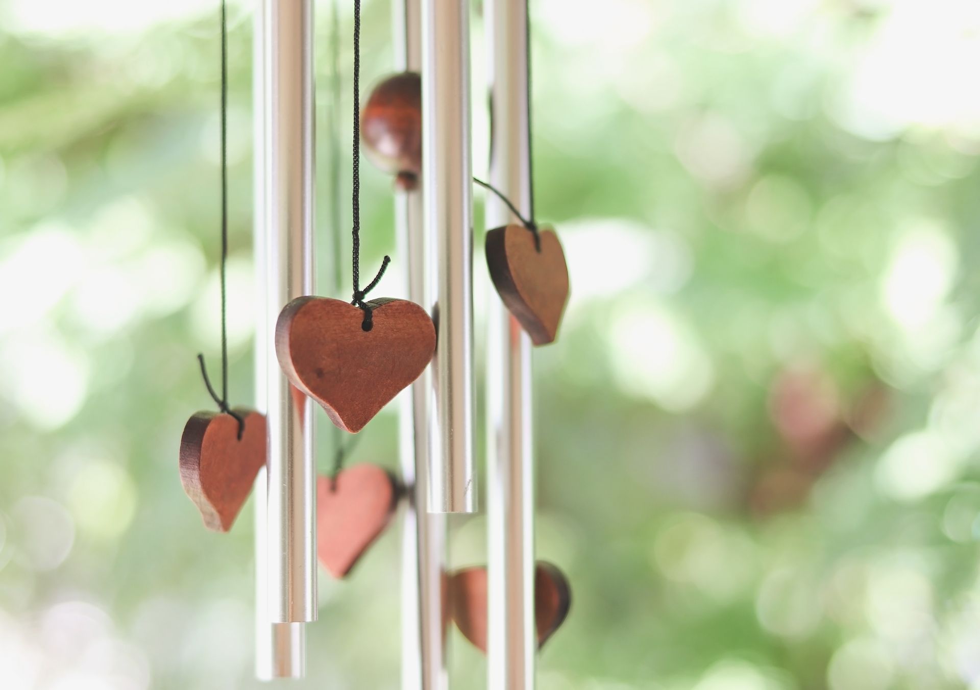 Des décorations en bois en forme de cœur, légèrement floues, sont suspendues près d'une fenêtre.