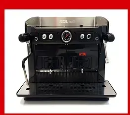 Una máquina de café negra con un reloj está sobre una mesa.