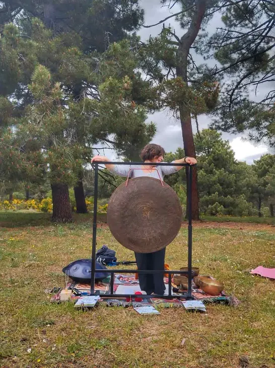 Una mujer está parada en un campo sosteniendo un gran gong.