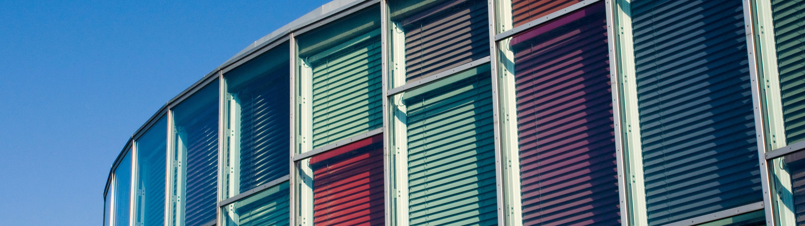 Ein Gebäude mit vielen Fenstern und einem blauen Himmel im Hintergrund.