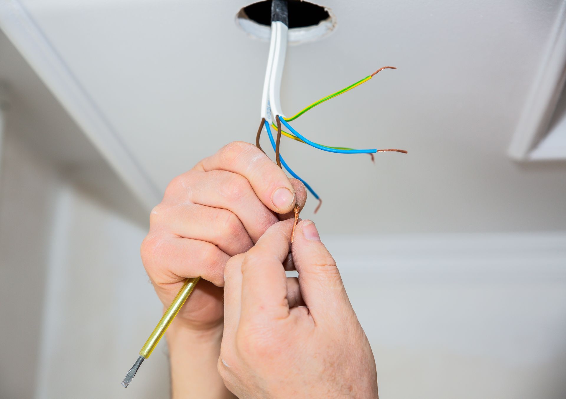 Une personne en train de manipuler des fils électriques.
