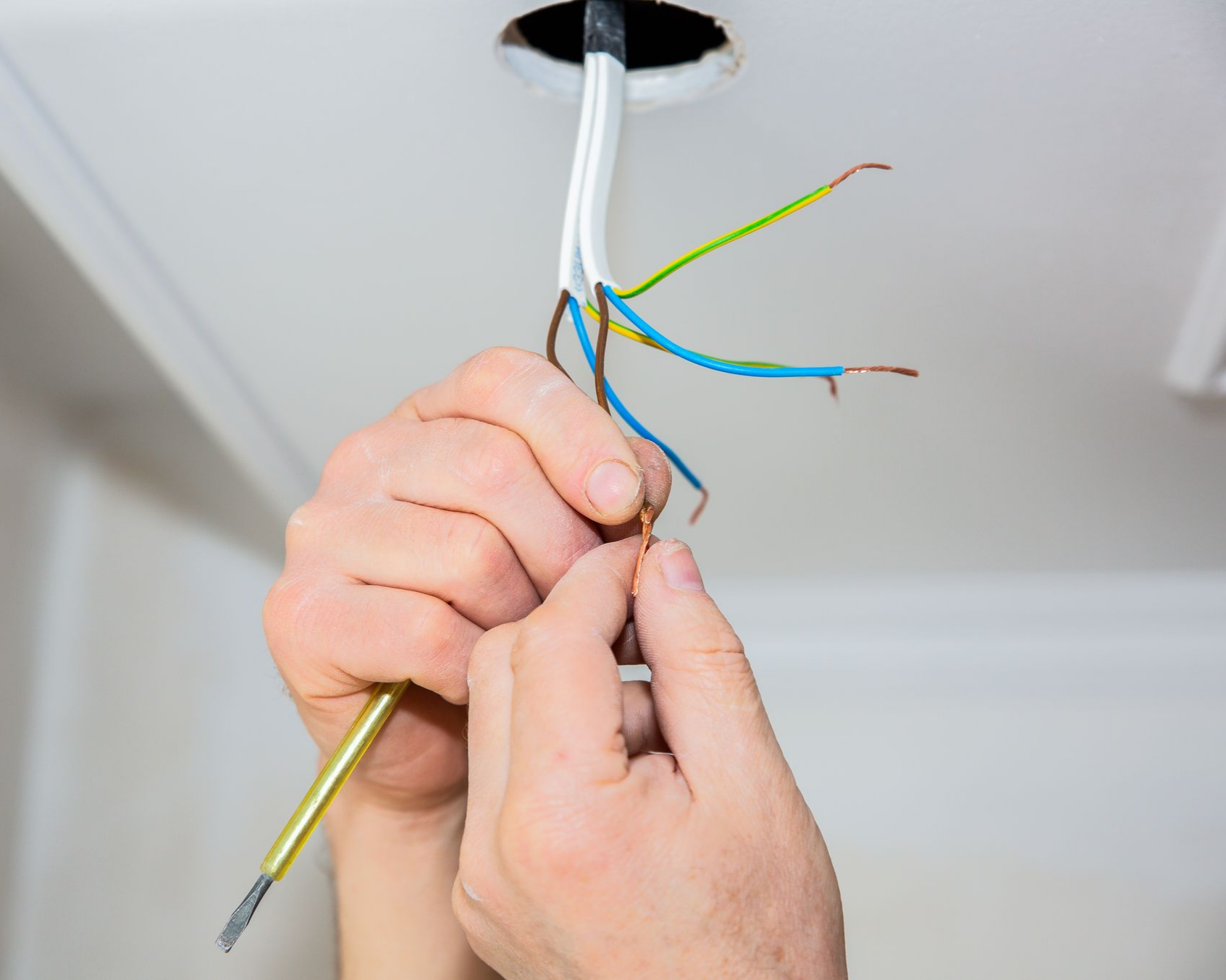 Une personne en train de manipuler des fils électriques.