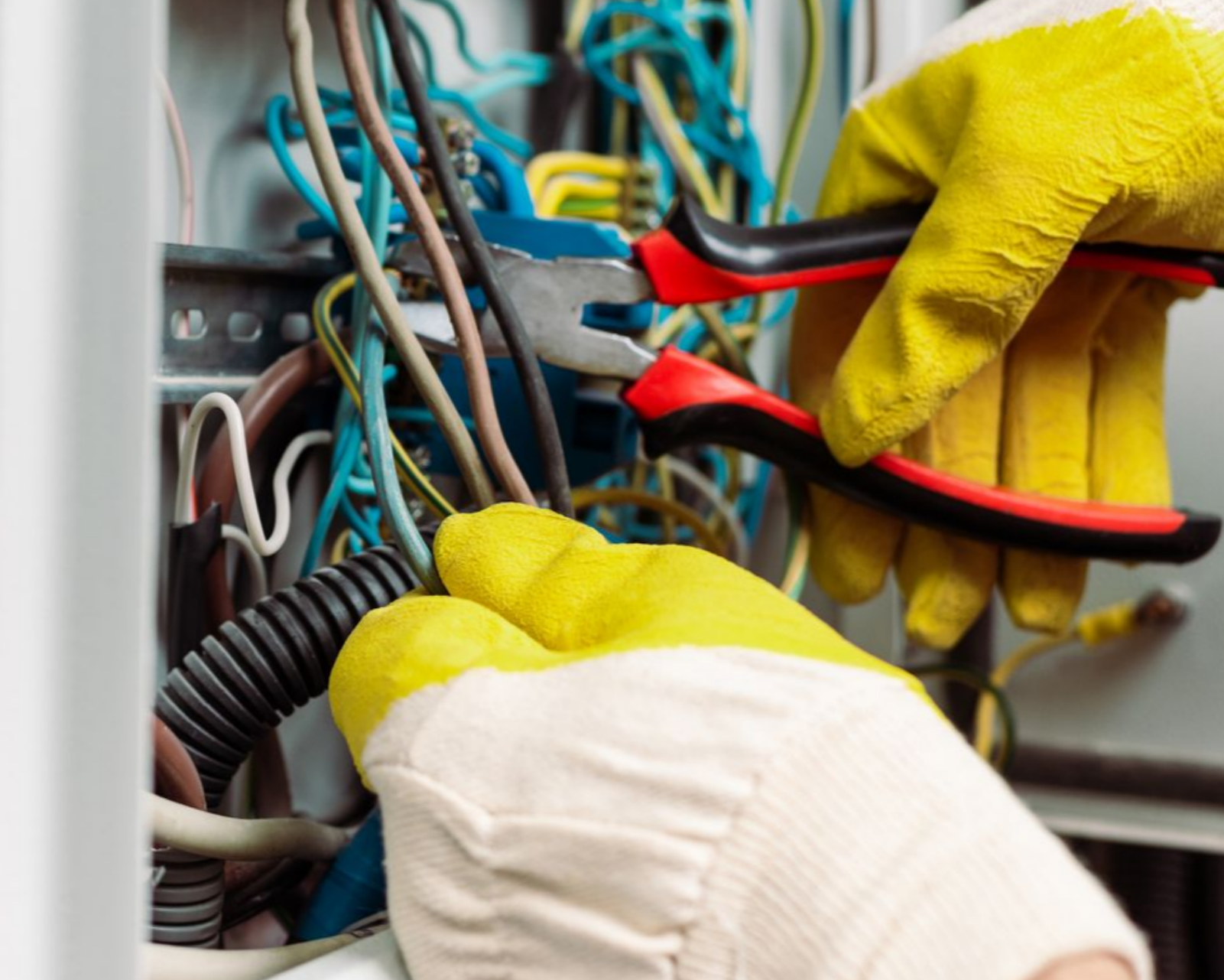 Une personne en train de travailler sur des câbles électriques.
