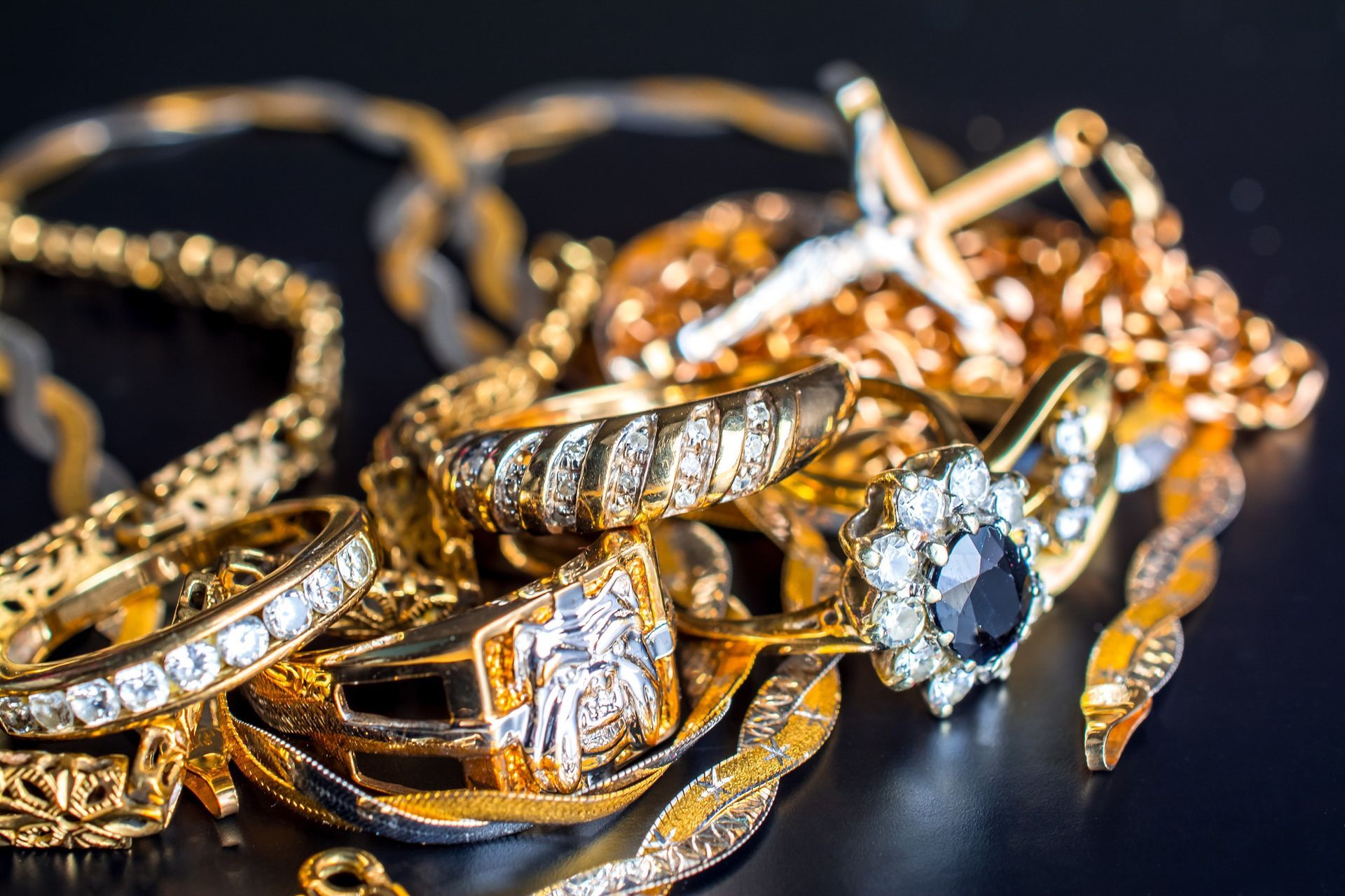 Una pila de joyas de oro sobre una superficie negra.