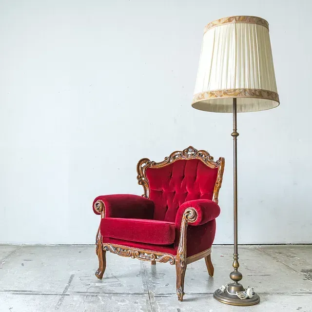 Una silla roja está al lado de una lámpara en el suelo.