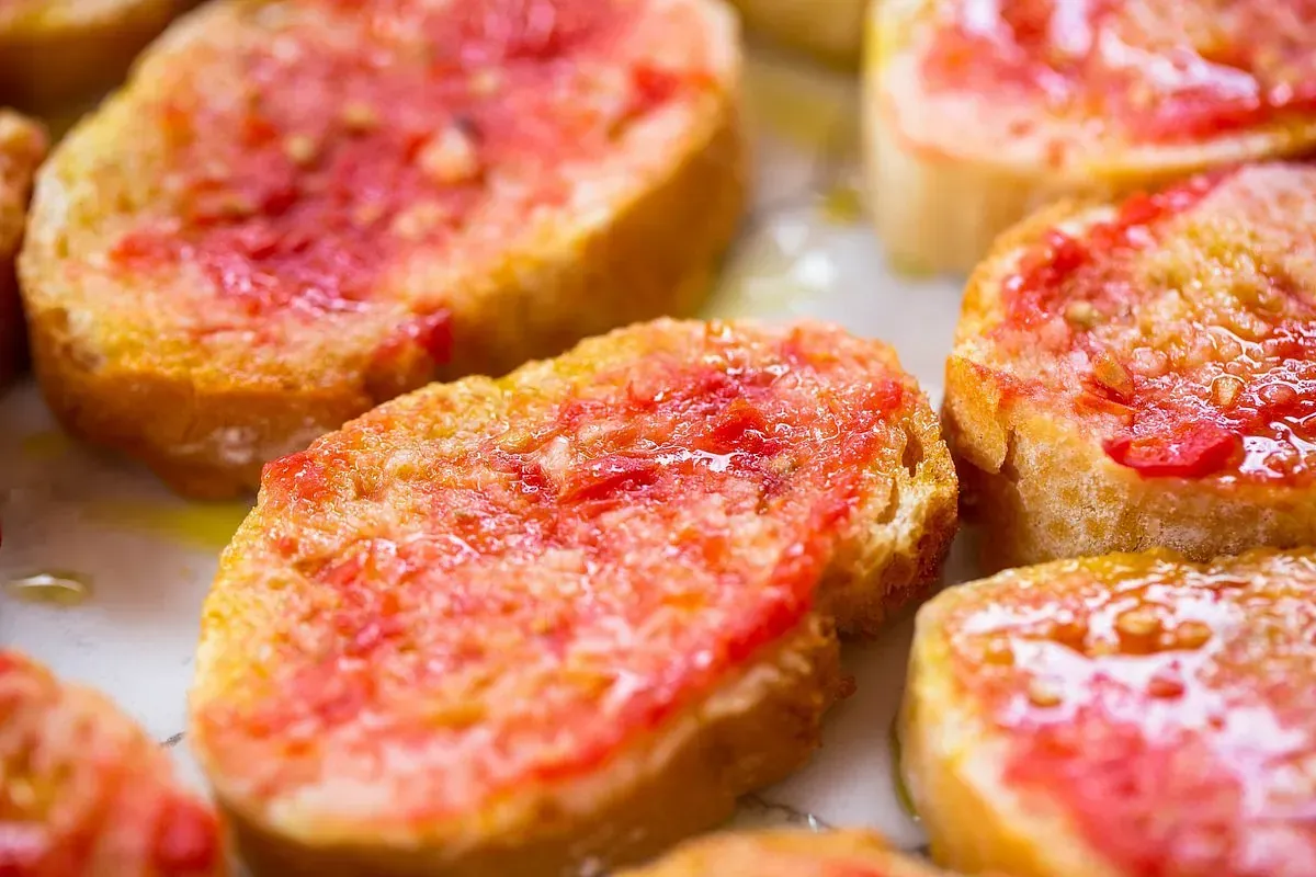 Rebanadas de pan tostado con tomate rojo y aceite.