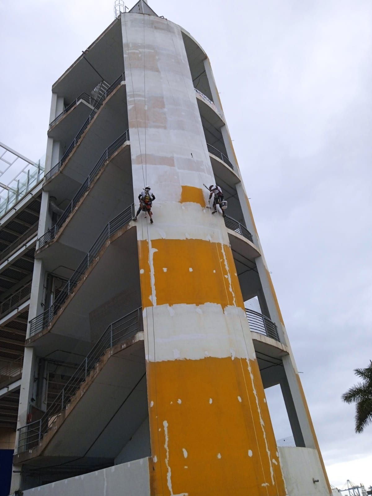 Dos hombres están subiendo por el costado de un edificio alto.
