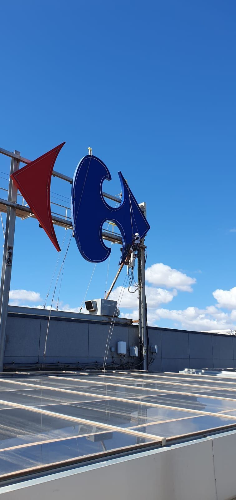 Un cartel azul y rojo en la parte superior de un edificio con un cielo azul de fondo.