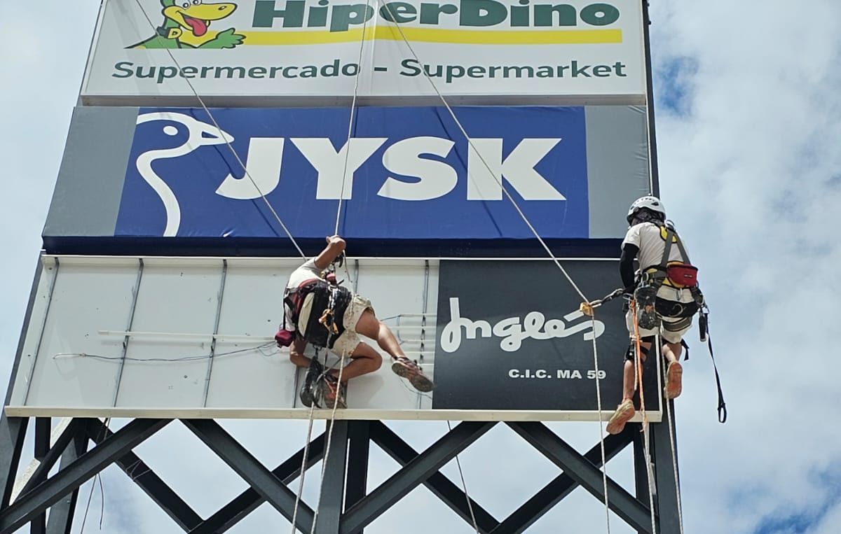 Dos hombres están trabajando en un cartel que dice Jysk