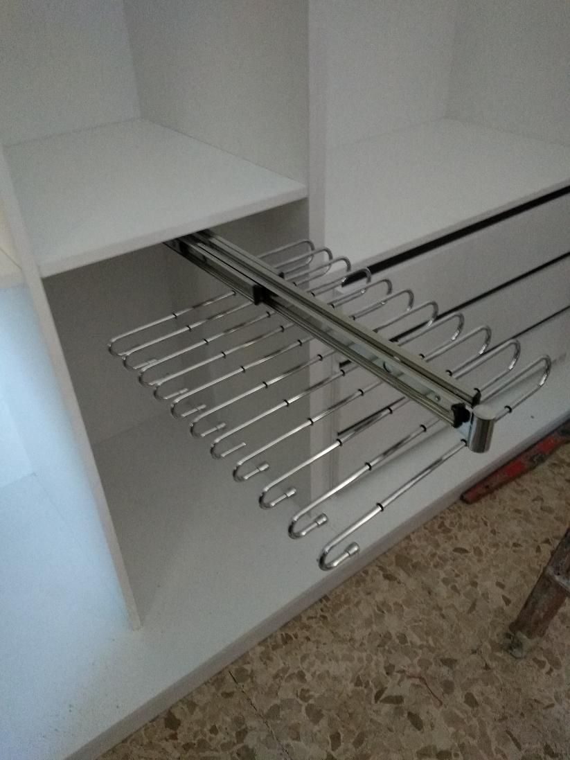 Organizador de armario extraíble para pantalones, varillas de metal cromado en un mueble blanco.