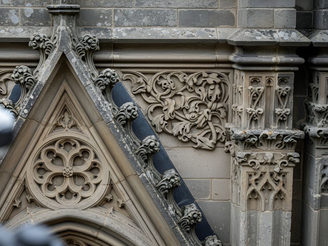 Détails architecturaux en pierre ornementée sur un bâtiment présentant des motifs floraux et géométriques sculptés.