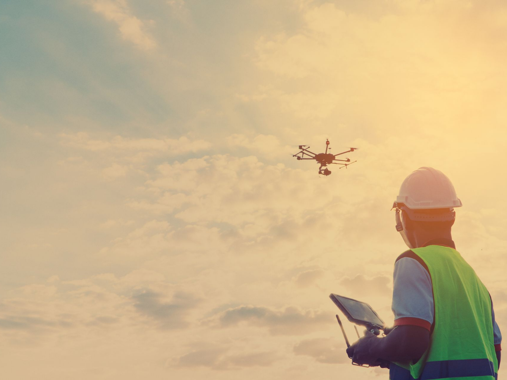 Un homme en tenue de sécurité pilote un drone en extérieur.
