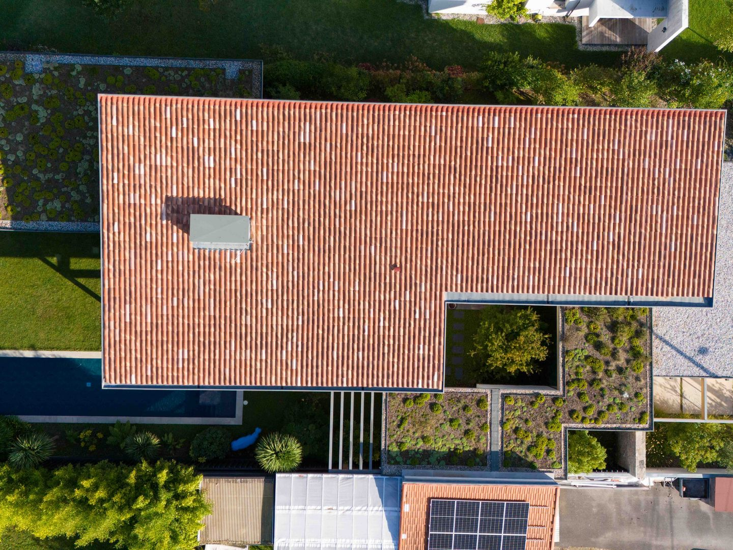 Vue aérienne d'une maison moderne avec un toit à crêtes couleur cuivre et une partie de toit végétalisée.