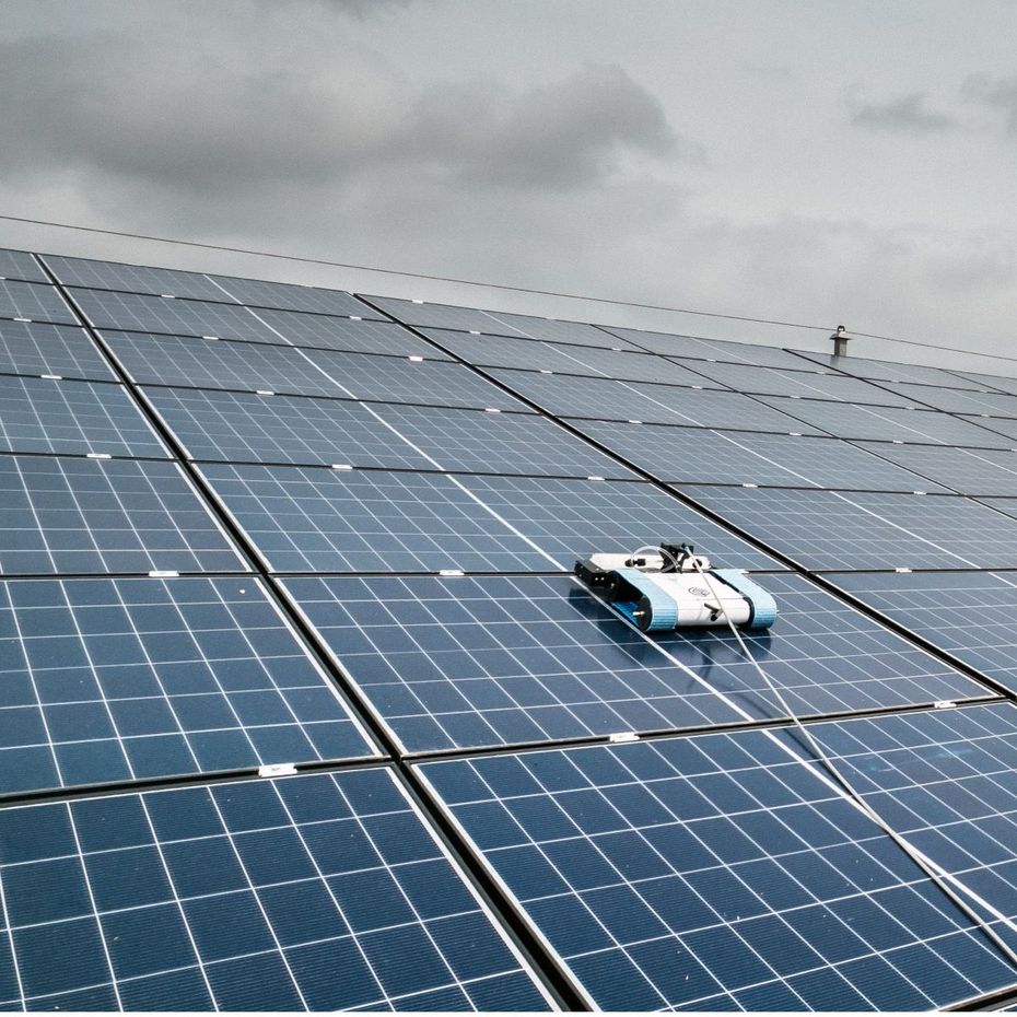 Robot de nettoyage en train de nettoyer des panneaux solaires.
