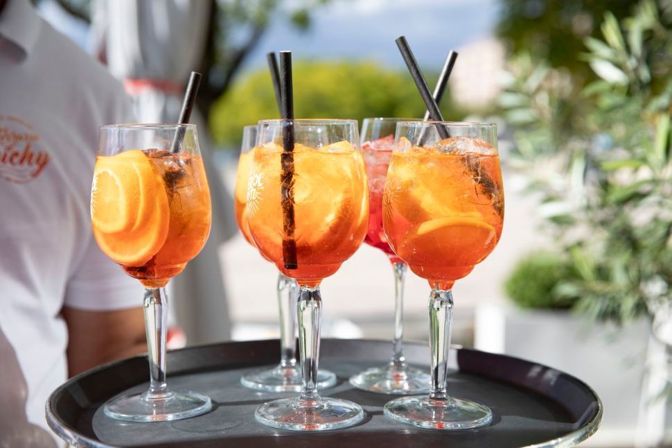 Cocktail dans un verre avec une paille, au bord de l'eau, paysage urbain en arrière-plan.