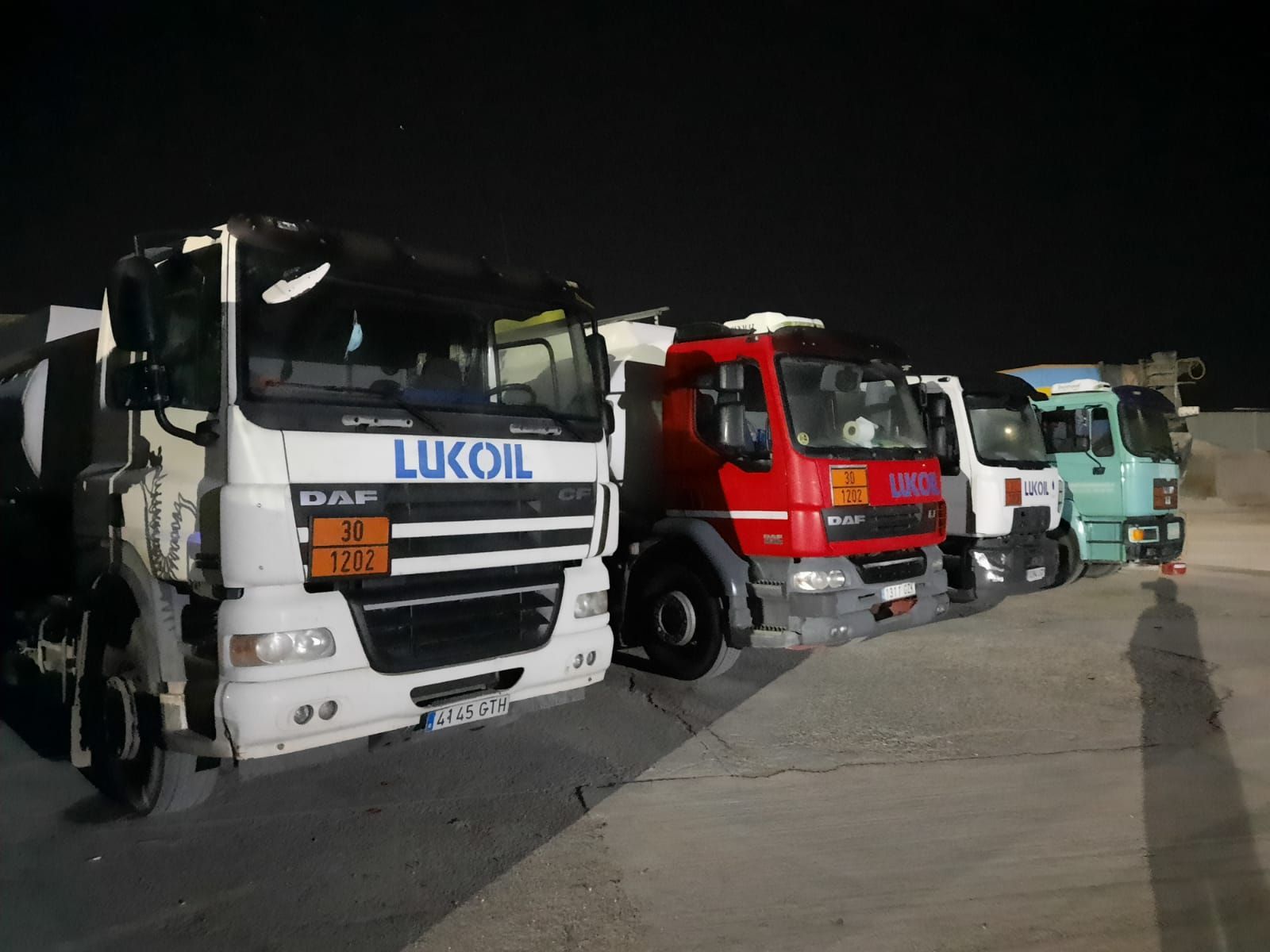 Una fila de camiones estacionados uno al lado del otro con uno que dice 'lukoil' en el frente