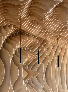 Techo ondulado de madera con tres lámparas colgantes negras.