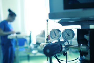 Una enfermera está de pie en el fondo de una habitación de hospital.