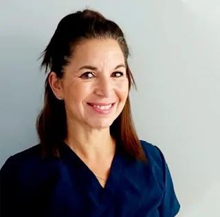 Una mujer con una blusa azul sonríe para la cámara.