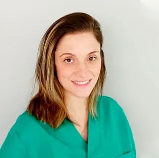 Una mujer con un matorral verde sonríe a la cámara.