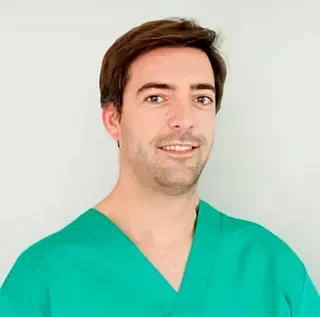 Un hombre con una blusa verde sonríe para la cámara.